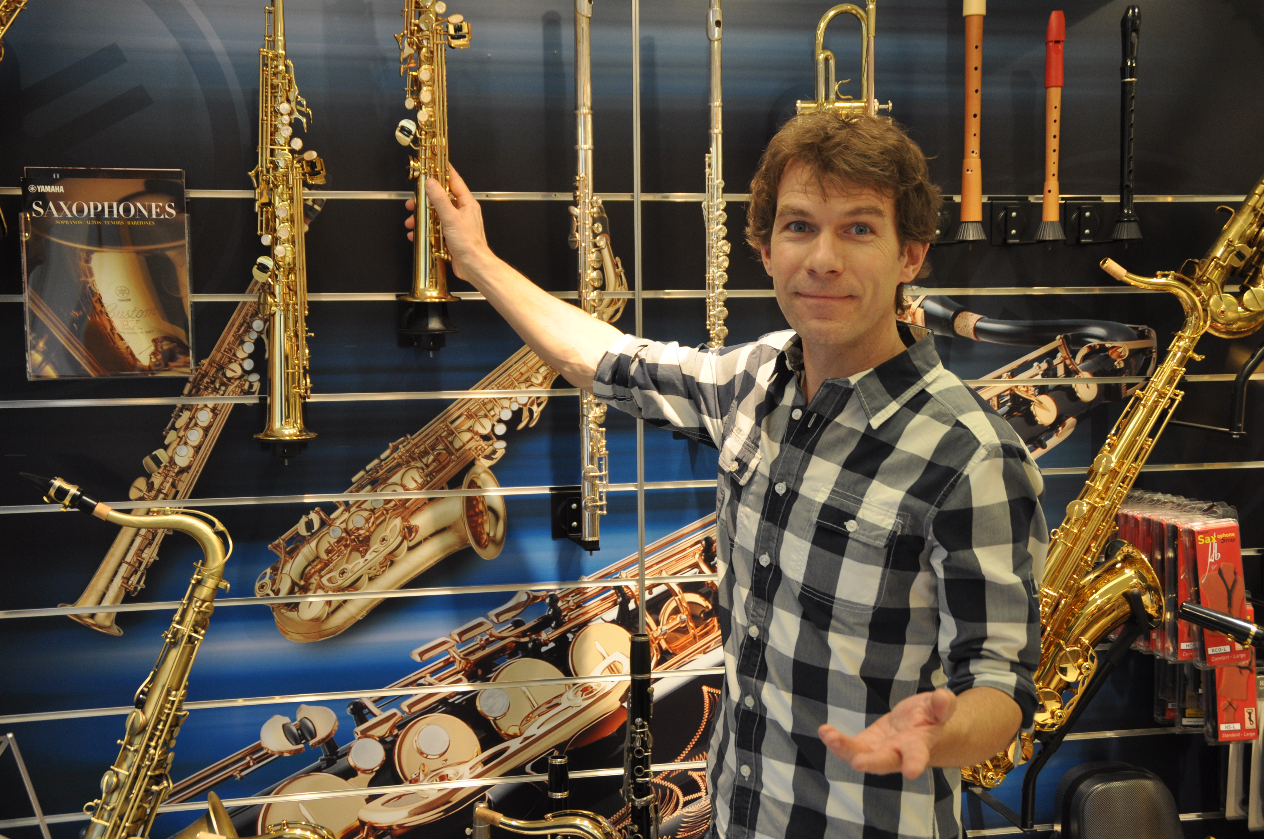 Matthias Rüdiger vor dem Instrumentenregal mit Saxophonen und Querflöten in der Musikwerkstatt Hofheim
